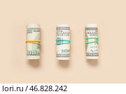 Пачки стодолларовых банкнот, связанные резинками на бежевом фоне. Стоковое фото, фотограф Pixel_shot / Фотобанк Лори