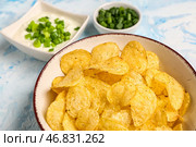 Миски с вкусной сметаной с нарезанным зеленым луком и картофельными чипсами на синем фоне. Стоковое фото, фотограф Pixel_shot / Фотобанк Лори