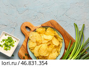 Миска вкусной сметаны с нарезанным зеленым луком и картофельными чипсами на голубом фоне. Стоковое фото, фотограф Pixel_shot / Фотобанк Лори