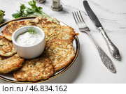 Тарелка вкусных кабачковых оладий с сметаной на фоне белого мрамора. Стоковое фото, фотограф Pixel_shot / Фотобанк Лори