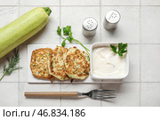 Доска с вкусными кабачковыми оладьями с сметаной на белом плиточном фоне. Стоковое фото, фотограф Pixel_shot / Фотобанк Лори