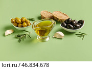 Миски с спелыми оливками и соусница с маслом на зеленом фоне. Стоковое фото, фотограф Pixel_shot / Фотобанк Лори