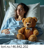 In a hospital room, a sick woman lies in bed, her eyes closed in a moment of respite. Beside her, a teddy bear brings warmth and comfort during a challenging time, embodying hope and strength. Стоковое AI-изображение, AI-художник Юлия Петровская / Фотобанк Лори