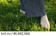Close-up of woman walking barefoot on green grass. Concept. Beautiful female feet tread on green grass. Woman steps barefoot on grass in park on sunny day. Стоковое фото, фотограф Данил Руденко / Фотобанк Лори