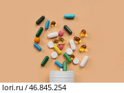 Банка с разноцветными разбросанными таблетками на оранжевом фоне. Стоковое фото, фотограф Pixel_shot / Фотобанк Лори
