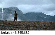 Man photographing mountain highness landscape. Clip. Rear view of a man hiker taking photos of heavy clouds and mountain tops. Стоковое фото, фотограф Данил Руденко / Фотобанк Лори