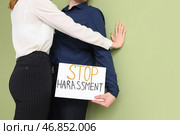 Бизнесмен держит лист бумаги с текстом "СТОП ДОМОГАТЕЛЬСТВА" и его коллега-женщина на зеленом фоне. Стоковое фото, фотограф Pixel_shot / Фотобанк Лори
