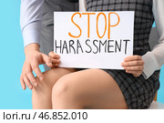 Бизнес-леди держит лист бумаги с текстом "СТОП ДОМОГАТЕЛЬСТВА", а её коллега-мужчина на синем фоне, крупным планом. Стоковое фото, фотограф Pixel_shot / Фотобанк Лори