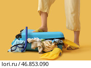 Женщина пытается закрыть чемодан на желтом фоне. Стоковое фото, фотограф Pixel_shot / Фотобанк Лори