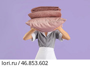 Женщина-уборщица с сложенным теплым клетчатым пледом и подушкой на сиреневом фоне. Стоковое фото, фотограф Pixel_shot / Фотобанк Лори