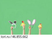 Женские руки, держащие ободки с ушками кролика и игрушечными цыплятами на зеленом фоне. Стоковое фото, фотограф Pixel_shot / Фотобанк Лори