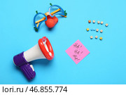 ДЕНЬ СМЕШАРИКА с мегафоном, смешными очками и клейкой запиской на голубом фоне. Стоковое фото, фотограф Pixel_shot / Фотобанк Лори
