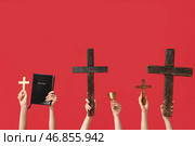 Женские руки с деревянными крестами, Священной Библией и чашей на красном фоне. Концепция Пятницы Страстей. Стоковое фото, фотограф Pixel_shot / Фотобанк Лори