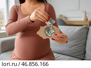 Молодая беременная женщина класть деньги в копилку дома, крупным планом. Концепция пособий по беременности. Стоковое фото, фотограф Pixel_shot / Фотобанк Лори