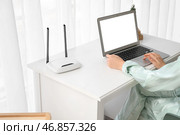 Женщина с Wi-Fi роутером, использующая ноутбук на столе дома, крупным планом. Стоковое фото, фотограф Pixel_shot / Фотобанк Лори