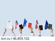 Руки, держащие избирательный ящик, паспорта, флаги США и ЕС на светлом фоне. Концепция выборов. Стоковое фото, фотограф Pixel_shot / Фотобанк Лори