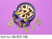 Тарелка с вкусными печеньями хаманташен, карнавальная маска и слово Пурим на цветном фоне. Стоковое фото, фотограф Pixel_shot / Фотобанк Лори