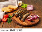 Доска с вкусной копченой мойвой на деревянном фоне, крупным планом. Стоковое фото, фотограф Pixel_shot / Фотобанк Лори