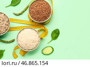 Миски с различными хлопьями, овощами и желтой измерительной лентой на зеленом фоне. Концепция диеты. Стоковое фото, фотограф Pixel_shot / Фотобанк Лори