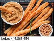 Деревянная доска с вкусным итальянским гриссини, хумусом и нутом на темном фоне, крупным планом. Стоковое фото, фотограф Pixel_shot / Фотобанк Лори