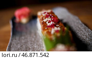 Lose up for sushi rolls on black tray standing on the table, Japanese traditional food. Стоковое фото, фотограф David Kashakhi / Фотобанк Лори