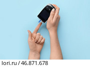 Женщина с помощью глюкометра на синем фоне. Концепция диабета. Стоковое фото, фотограф Pixel_shot / Фотобанк Лори