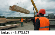 Worker in a construction site transporting a wooden bars using crane. Стоковое фото, фотограф David Kashakhi / Фотобанк Лори