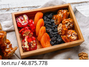 Коробка вкусных кусочков чурчхелы с курагой и изюмом на белом деревянном фоне. Стоковое фото, фотограф Pixel_shot / Фотобанк Лори