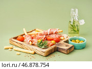 Деревянная доска вкусного итальянского гриссини с хамоном на зеленом фоне. Стоковое фото, фотограф Pixel_shot / Фотобанк Лори