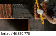 Top view of an industrial worker levelling ceramic brick wall with a wooden hammer. Стоковое фото, фотограф David Kashakhi / Фотобанк Лори