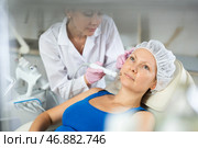 Young doctor doing RF lifting procedure for face lifting of adult woman laying in spa center. Smoothes wrinkles and tightens skin machine. Стоковое фото, фотограф Яков Филимонов / Фотобанк Лори