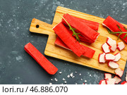 Деревянная доска с вкусными крабовыми палочками на зеленом фоне. Стоковое фото, фотограф Pixel_shot / Фотобанк Лори