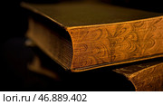 Close up of vintage thick book lying on flat surface isolated on black background. Стоковое фото, фотограф David Kashakhi / Фотобанк Лори