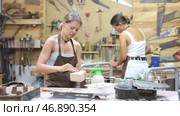 Positive young girls in apron processing clay bowls in carpenter's workshop. Стоковое видео, видеограф Яков Филимонов / Фотобанк Лори