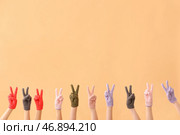 Женщины в теплых перчатках показывают победный жест на бежевом фоне. Стоковое фото, фотограф Pixel_shot / Фотобанк Лори
