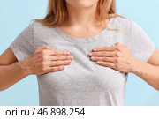 Зрелая женщина чувствует дискомфорт в груди на цветном фоне. Концепция осведомленности о раке. Стоковое фото, фотограф Pixel_shot / Фотобанк Лори