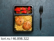 Контейнер для доставки еды с вкусной перловой крупой, котлетами и овощами на темном фоне. Стоковое фото, фотограф Pixel_shot / Фотобанк Лори