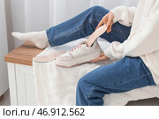 Молодая женщина вставляет ортопедическую стельку в кроссовок на скамейке дома, крупный план. Стоковое фото, фотограф Pixel_shot / Фотобанк Лори