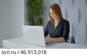 Action.A striking woman with short hair sits at a white computer and works at a desk in black clothes. Стоковое фото, фотограф David Kashakhi / Фотобанк Лори