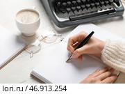 Женщина пишет что-то в блокноте, очки, чашка кофе и пишущая машинка на светлом деревянном столе, крупный план. Стоковое фото, фотограф Pixel_shot / Фотобанк Лори