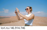 Tourist woman using cell phone for shooting, standing in desert. Стоковое фото, фотограф David Kashakhi / Фотобанк Лори