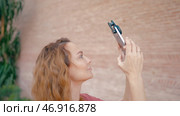A beautiful woman with long hair who shoots videos on an iPhone 13 pro with amazing accessories on it. Стоковое фото, фотограф David Kashakhi / Фотобанк Лори