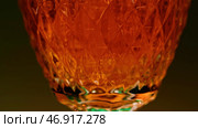 Close up of pouring whiskey into a glass on a colorful blurred wall background. Стоковое фото, фотограф David Kashakhi / Фотобанк Лори