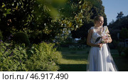 Action.Young people in a summer park with bright flowers and trees pose in wedding dresses separately. Стоковое фото, фотограф David Kashakhi / Фотобанк Лори