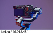 A rotating tripod for shooting with an attached camera on a purple background. Редакционное фото, фотограф David Kashakhi / Фотобанк Лори