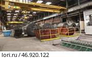 An overhead crane - Coil tong carrying a steel coil to a designated place in an automated warehouse storage facility. Стоковое фото, фотограф David Kashakhi / Фотобанк Лори