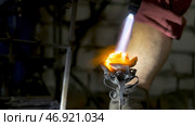 Blacksmith aligns leaves of iron rose and makes the final shape of the flower. Стоковое фото, фотограф David Kashakhi / Фотобанк Лори