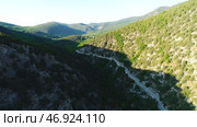 Aerial view of road going through a green mountains covered with shrubs and grass against blue sky in subber day. Стоковое фото, фотограф David Kashakhi / Фотобанк Лори