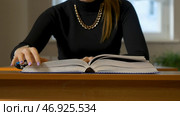 Woman sitting at the table leafing through the book. Стоковое фото, фотограф David Kashakhi / Фотобанк Лори