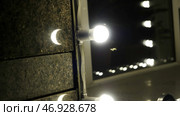 Close up of moths and flies fly near the lamp on a building wall at night. Стоковое фото, фотограф David Kashakhi / Фотобанк Лори